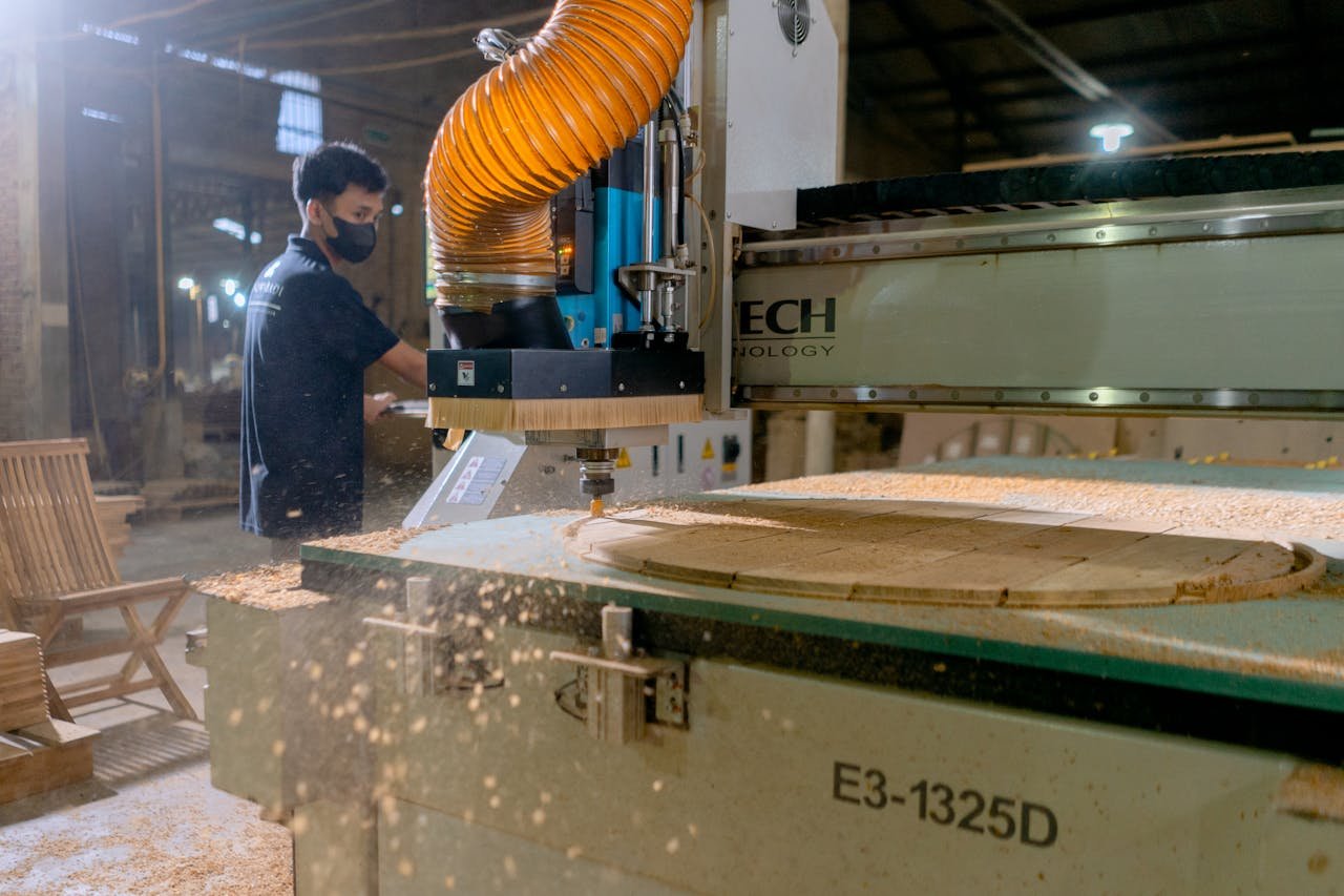 A carpenter operates a CNC machine in a factory, showcasing modern woodworking technology.